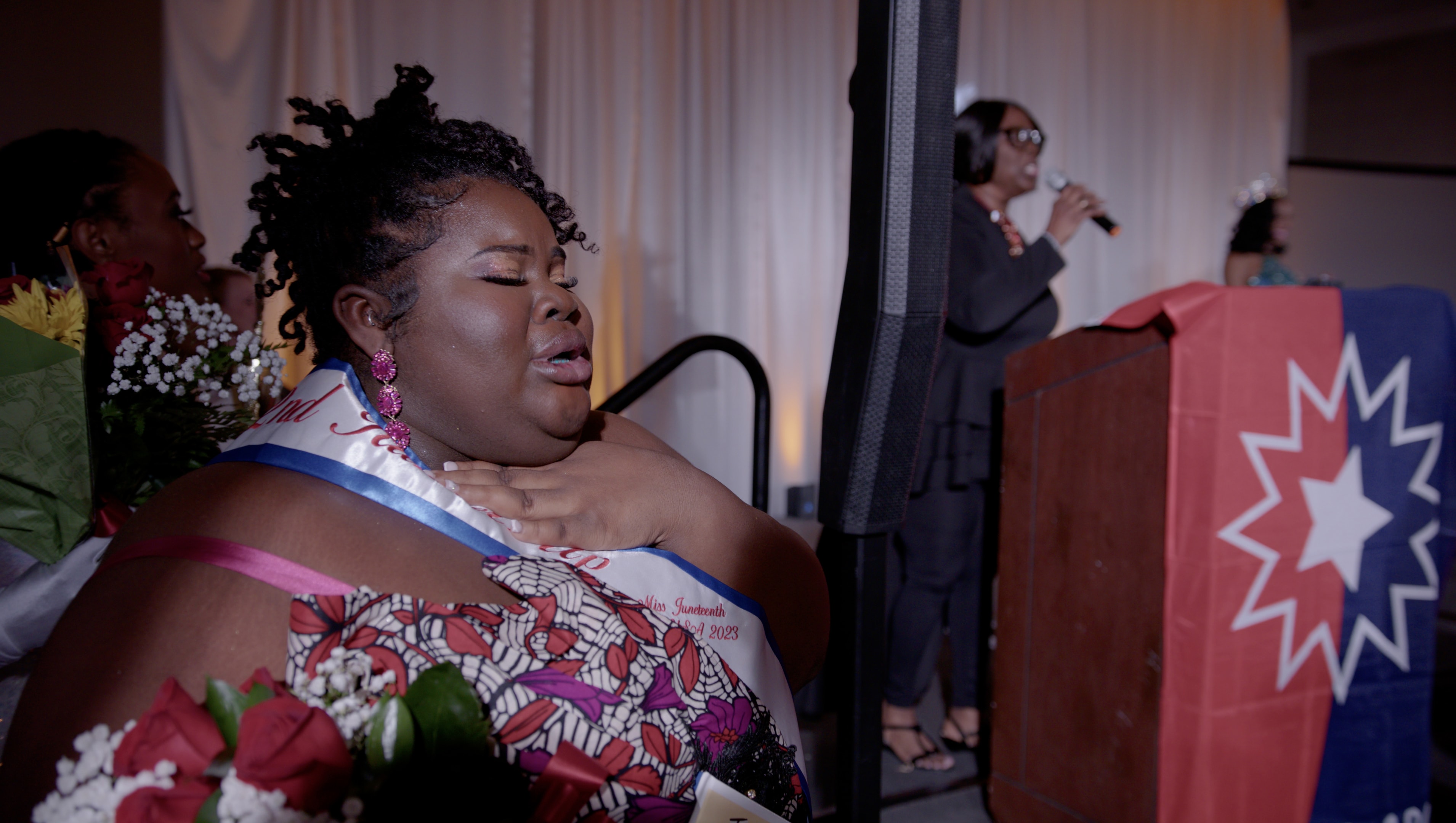 Miss Juneteenth contestant singing with eyes closed at podium