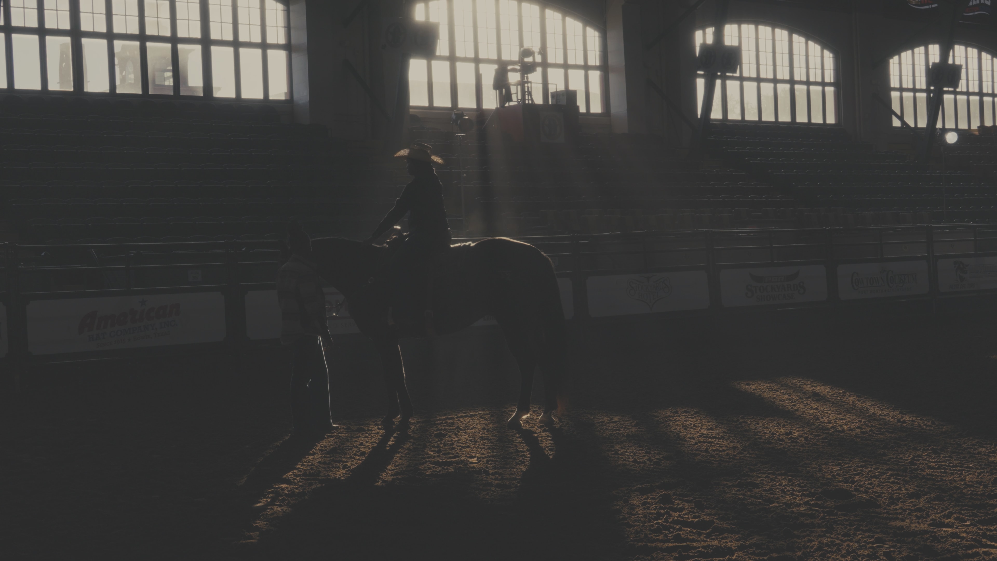 Silhouette of rider on horseback in a sunlit rodeo arena