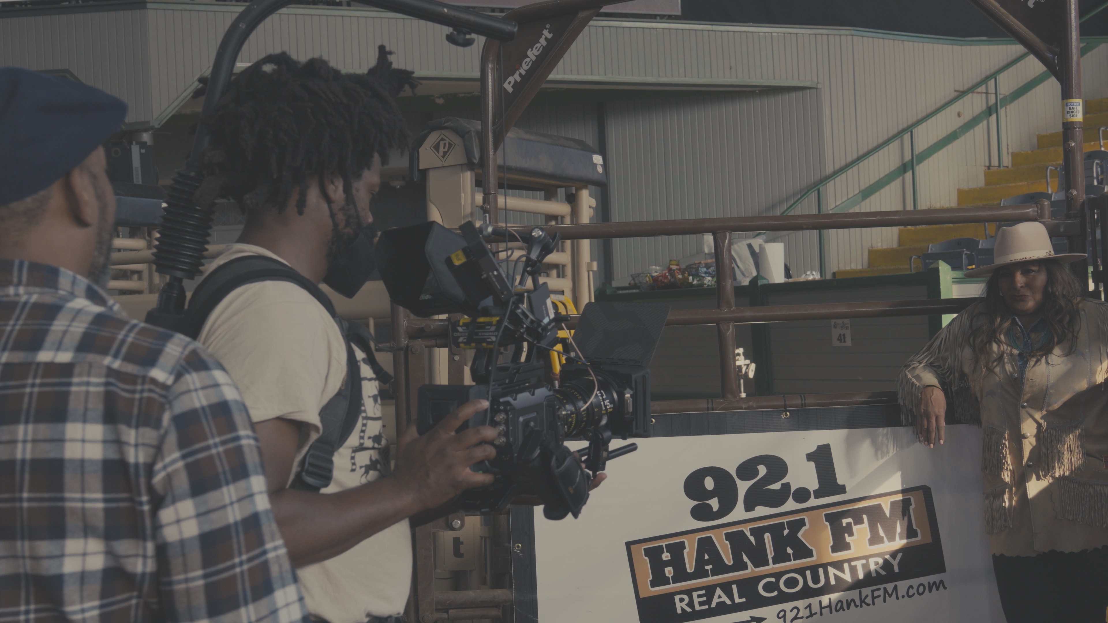 Camera operator filming subject at 92.1 Hank FM rodeo chute