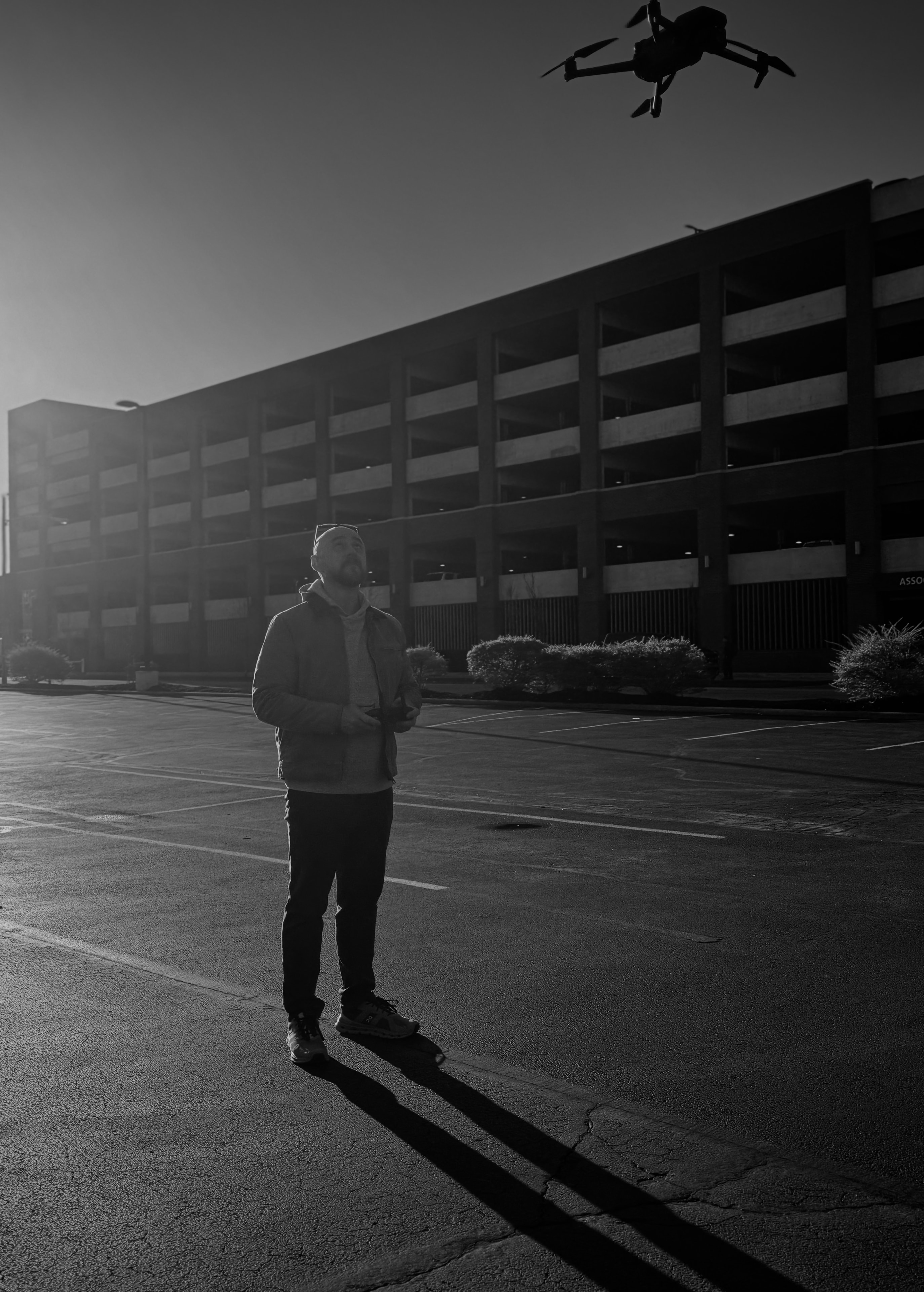 Cinematographer flying a drone in a parking lot at golden hour