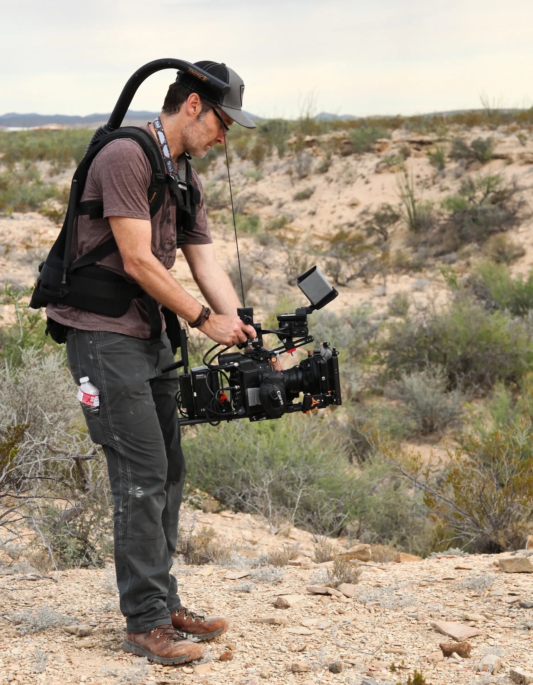 Cinematographer operating a gimbal rig on desert location