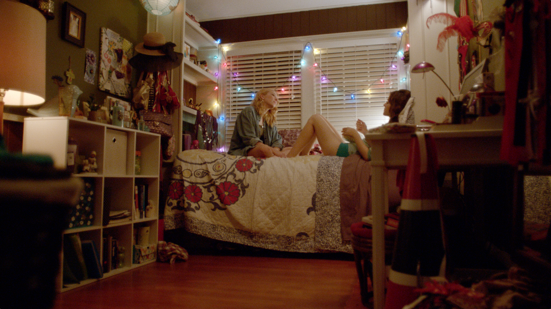 Two young women talking in a colorful bedroom with string lights