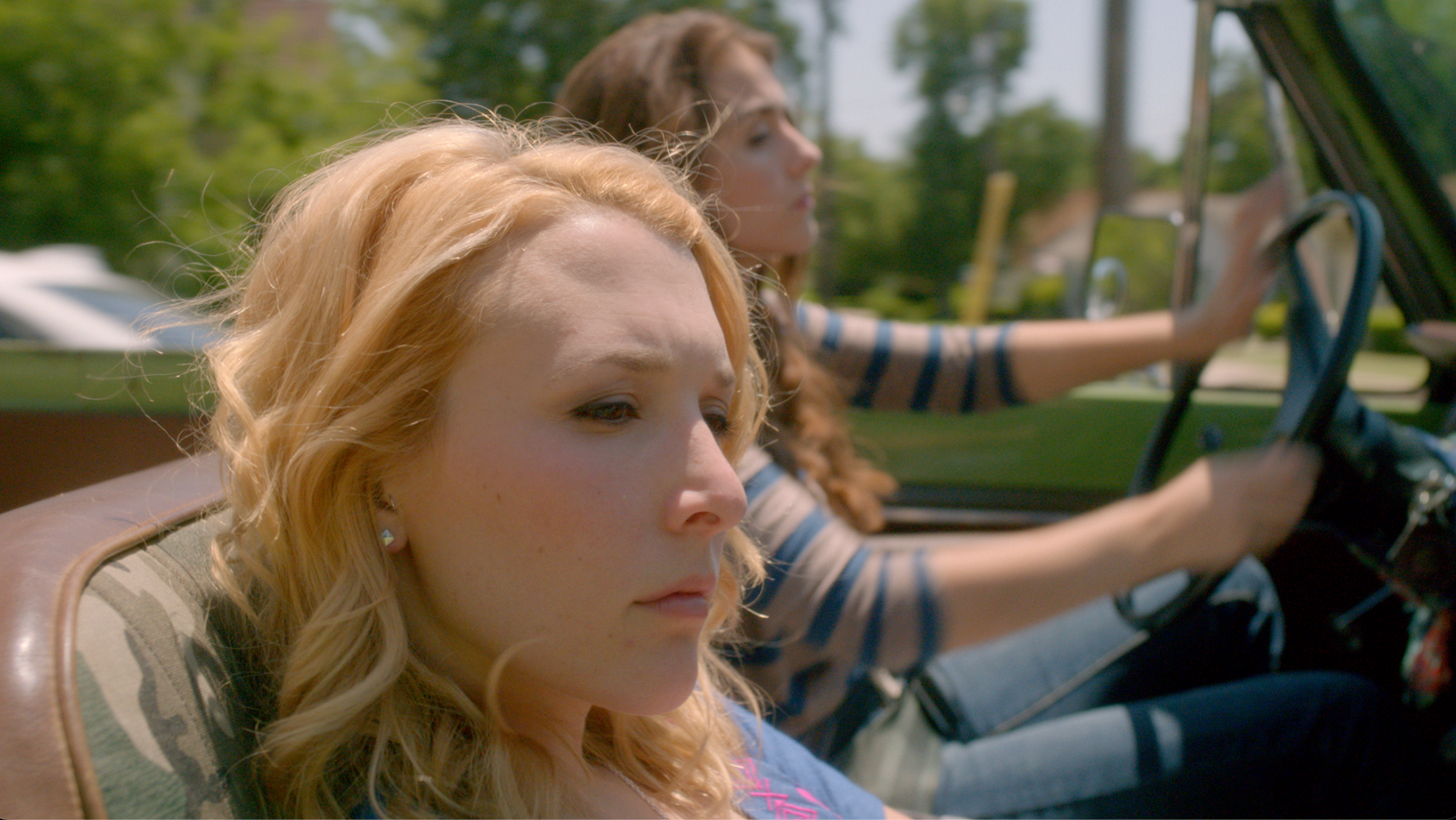 Red-haired girl in convertible car with friends on a sunny day