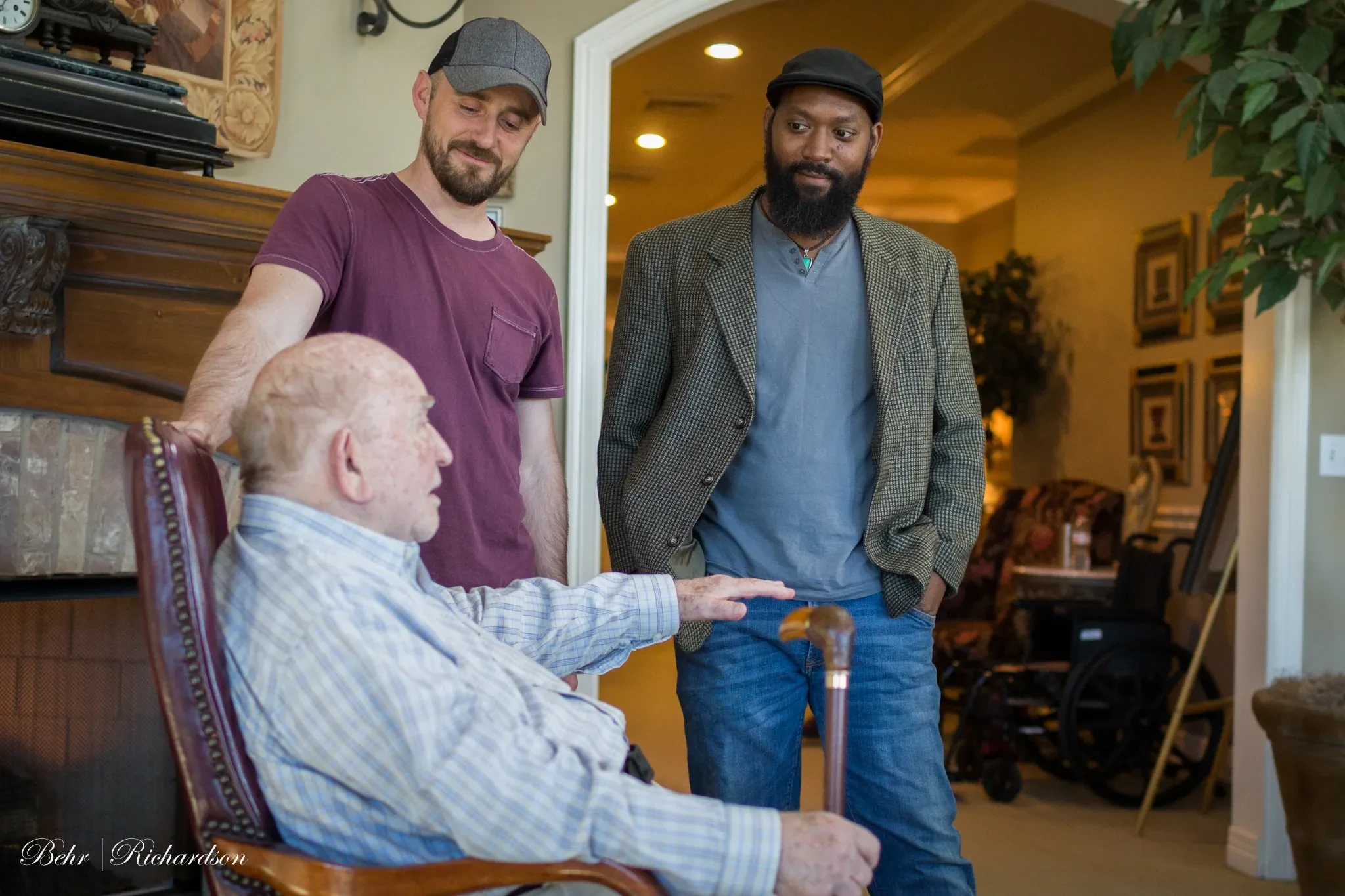 Two filmmakers with Ed Asner seated in armchair