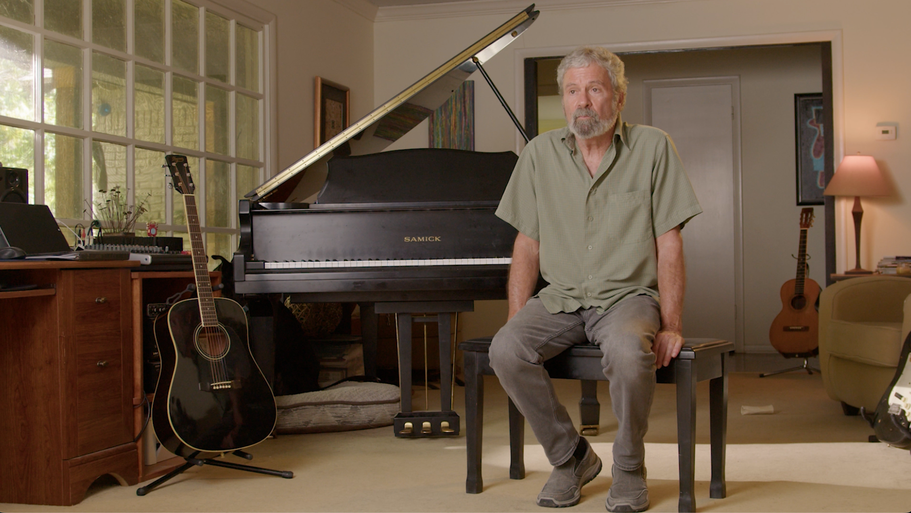 Musician seated at grand piano in home studio