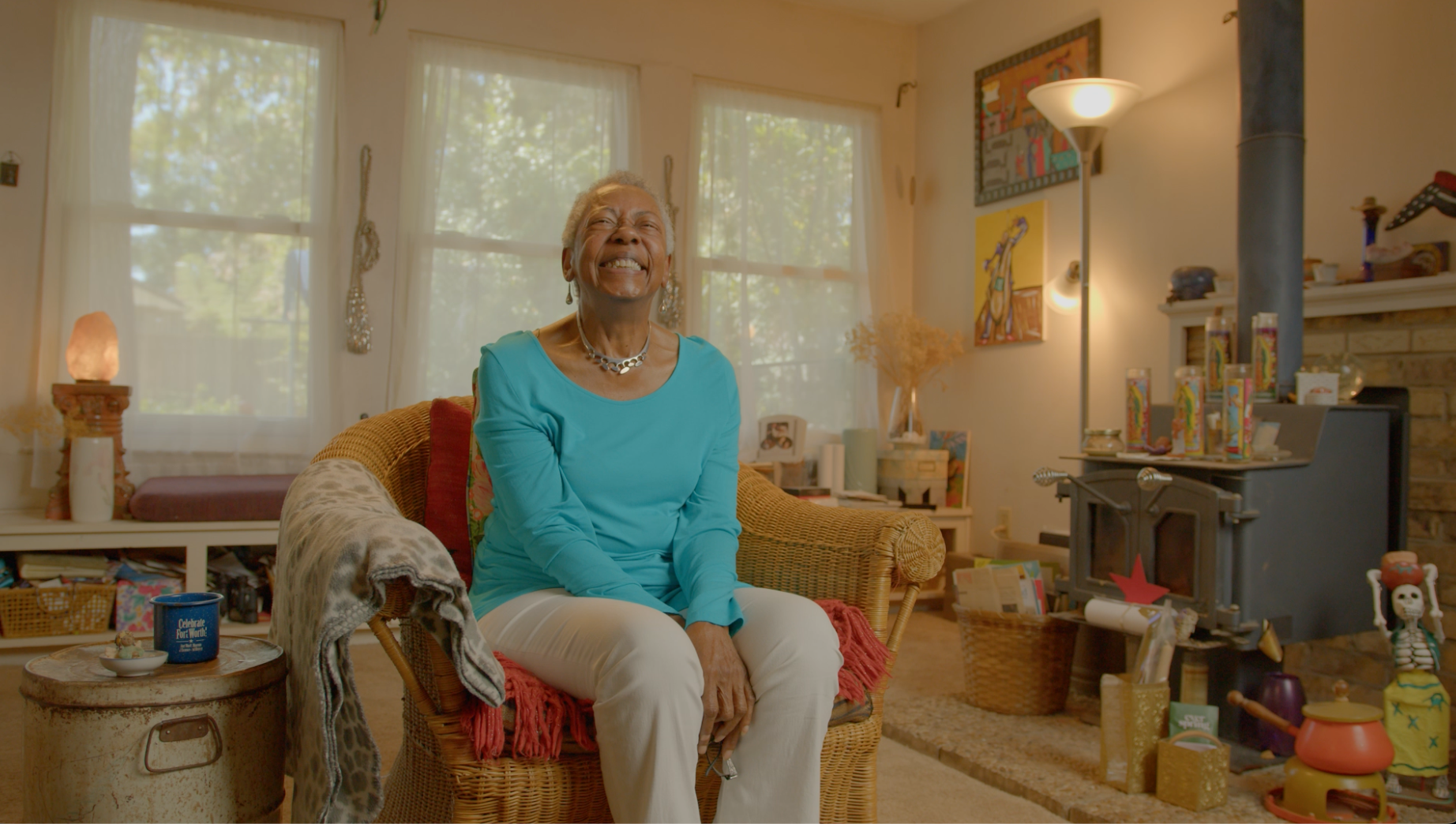 Woman in turquoise top laughing joyfully in colorful living room