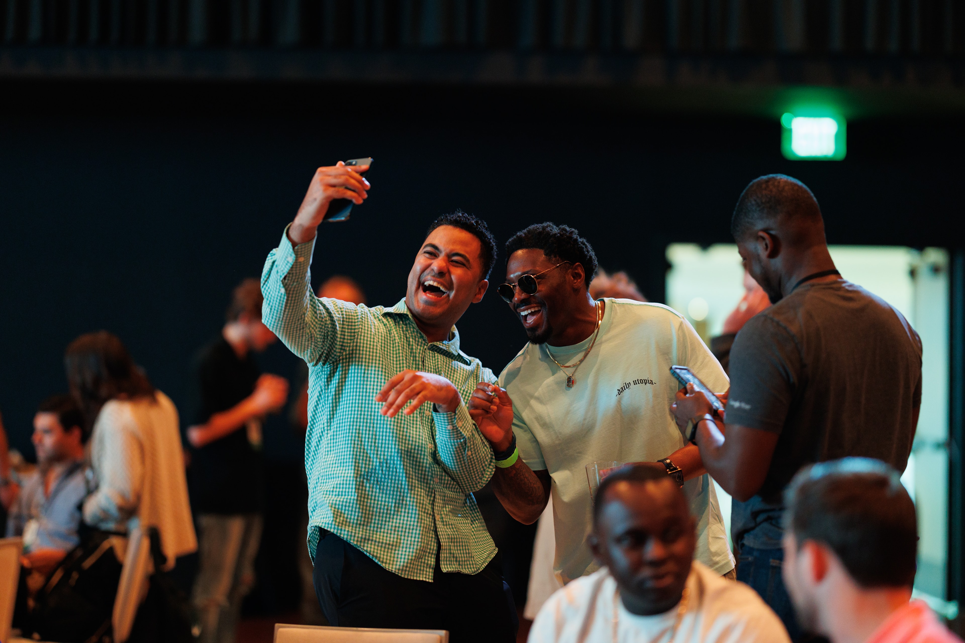 Two men laughing and taking a selfie at an event