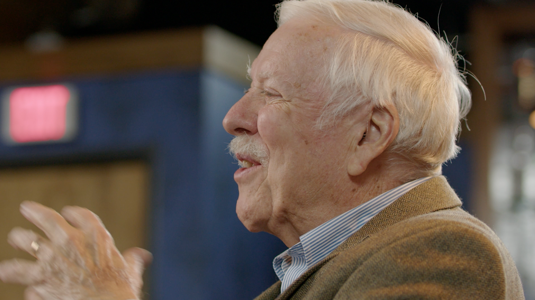 Elderly man in profile laughing warmly at an event